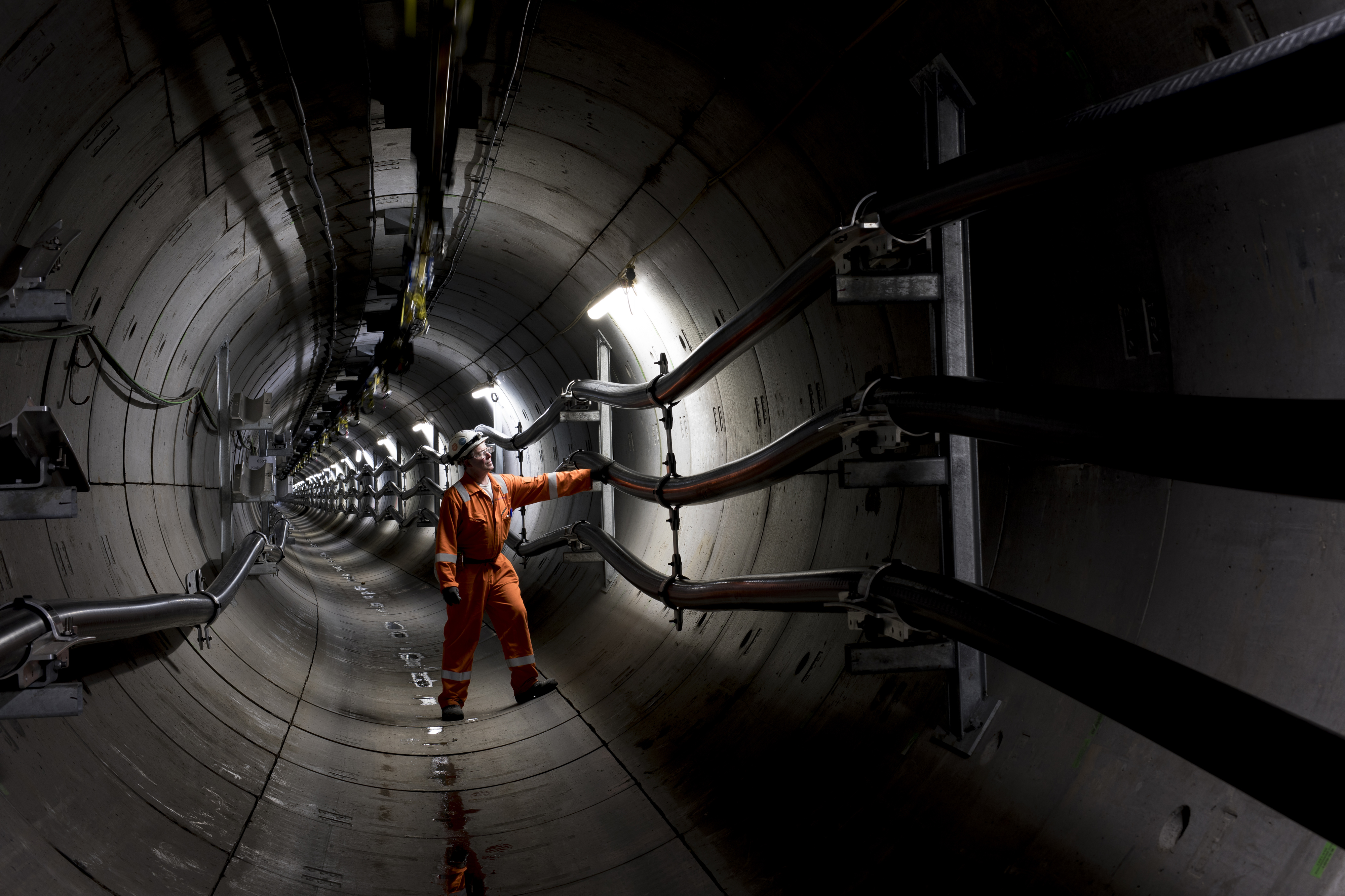 Man in orange jumpsuit stands inside an underground power tunnel