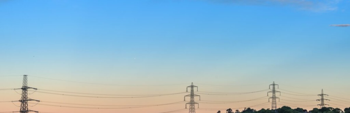 Transmission electricity pylons and overhead lines over estuary in Wales at sunrise